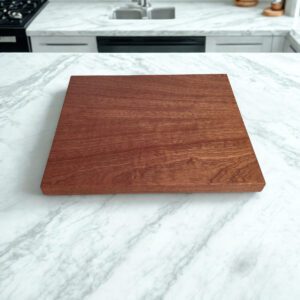Cherry cutting board with smooth edge grain surface on marble countertop