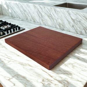 Walnut homestead cutting board placed beside stove on white marble countertop