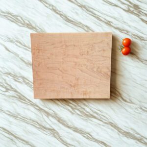 Maple cutting board with slim profile shown on a light stone kitchen countertop